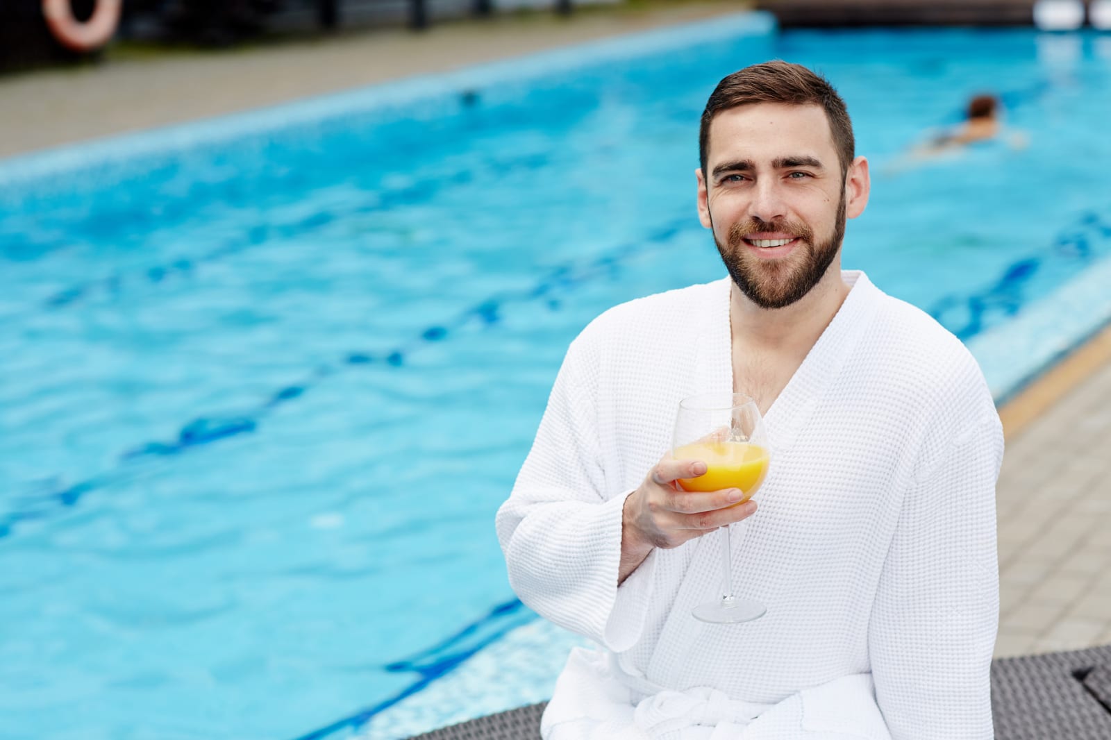 Pool owner relaxing at the edge of a backyard swimming pool